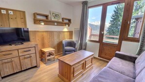Una sala de estar con muebles de madera, un televisor, un sofá, una mesa y una silla.