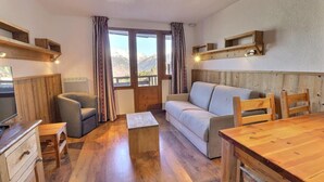 A cozy room with a sofa, a wooden table, and a TV.