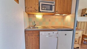 A compact kitchen with wooden cabinets, a microwave, a dishwasher, and a sink.