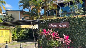 Un cartel con la inscripción 'Pouso Abare' frente a un edificio de techo de tejas y un corredor cubierto.