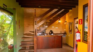 Interior de un restaurante con una escalera de madera, una barra y un extintor en la pared.
