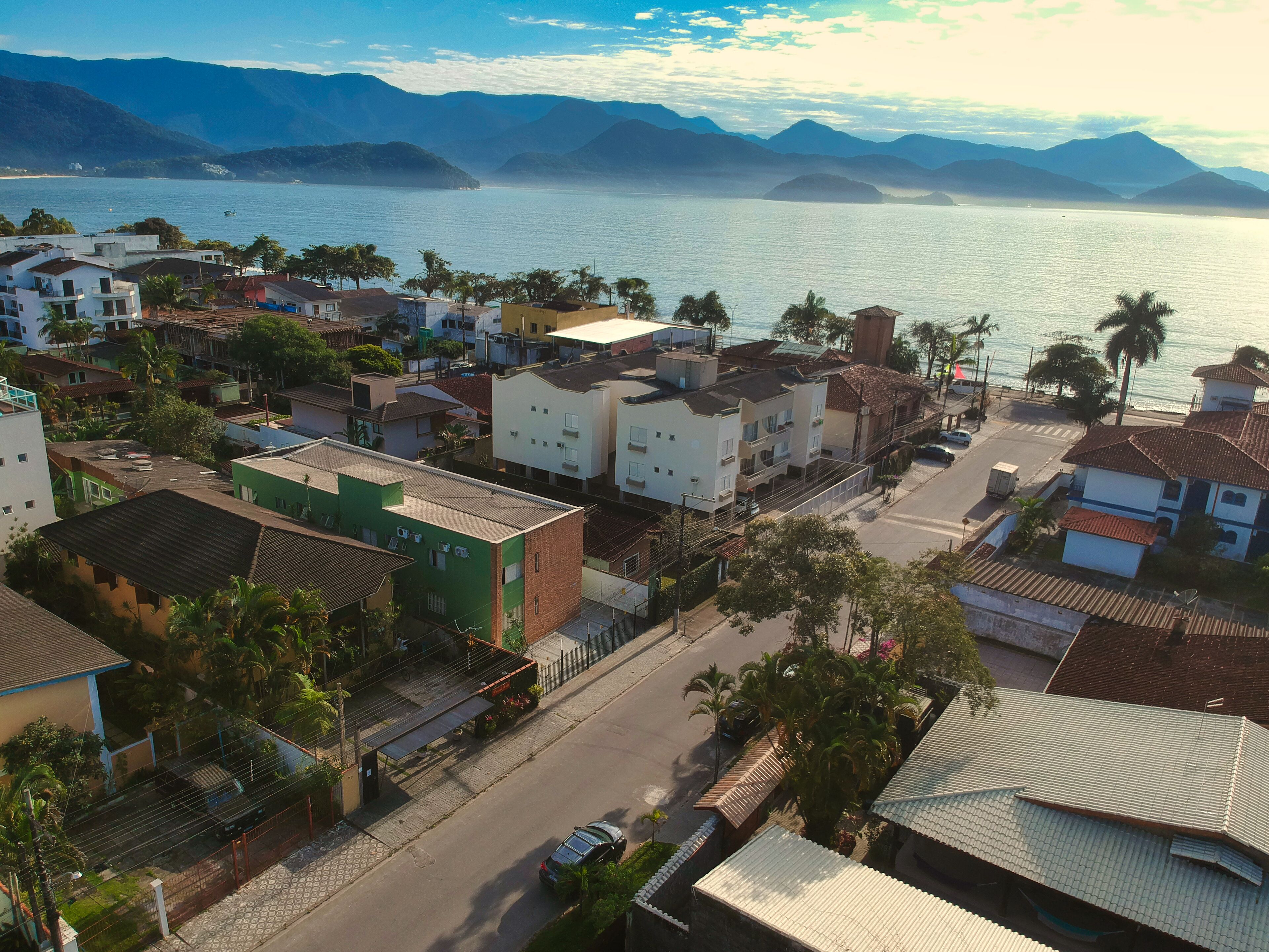 Un pueblo costero con edificios a lo largo de la calle, vista despejada al mar y montañas al fondo.