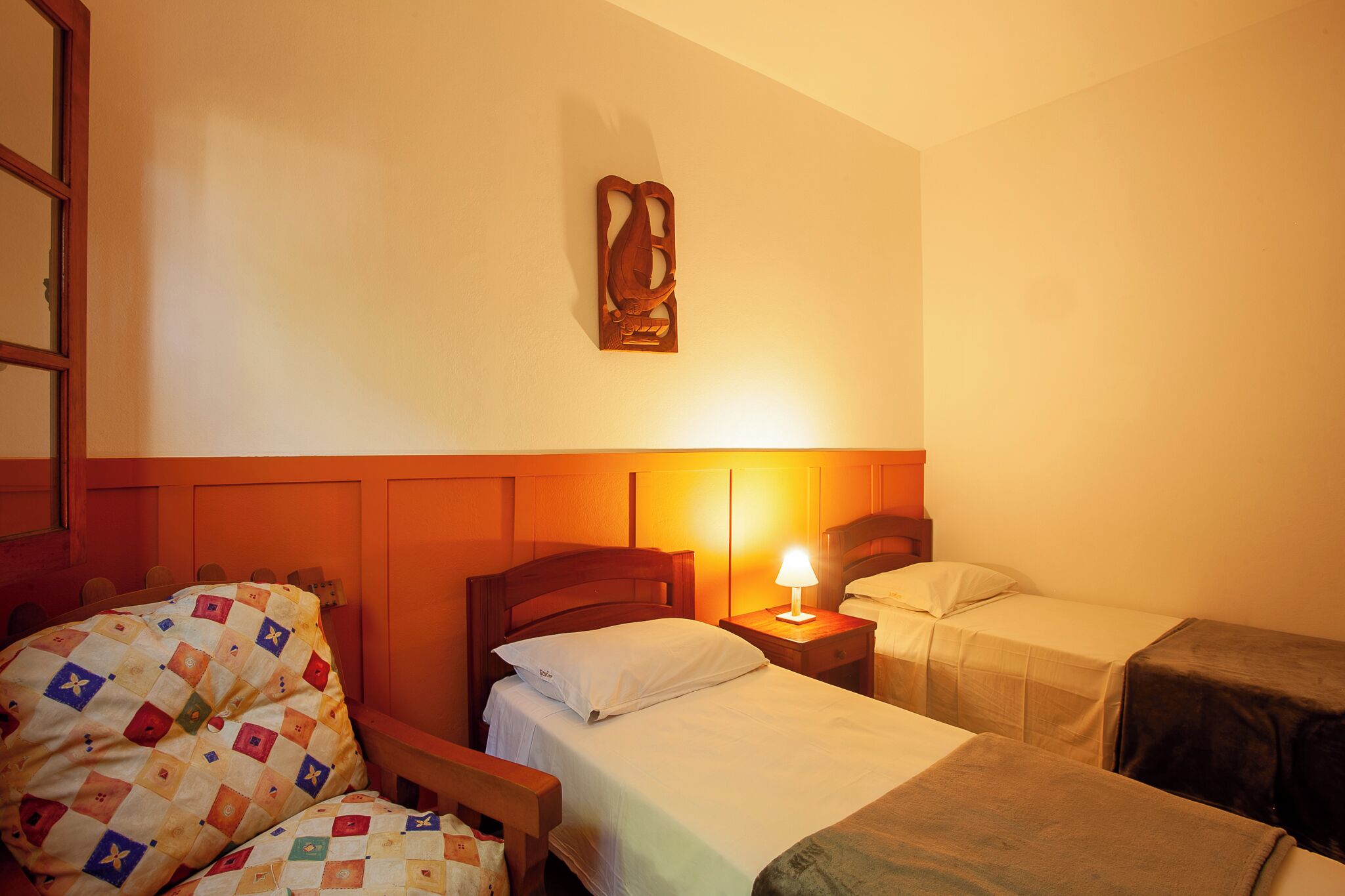 Quarto de hotel com cabeceira de madeira, luminária de cabeceira, colcha acolchoada e mesa de cabeceira de madeira.