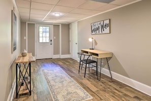 A hallway with a wooden floor, a rug, a desk with a chair, and a wall sign that reads "this is our happy place." - 21 Mi to Atlanta: Getaway w/ Fire Pit! (Jonesboro)