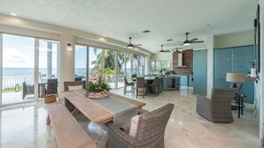 A spacious living area with a large wooden table, wicker chairs, and a view of the ocean. - Bakers Bay: Key Largo Sunset Haven (Key Largo)