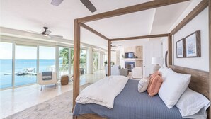 A spacious bedroom with a four-poster bed, a large window overlooking the sea, and a balcony with a view of the ocean. - Bakers Bay: Key Largo Sunset Haven (Key Largo)