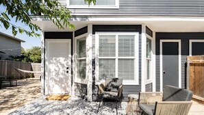 A house with a covered patio area featuring a patterned rug, two chairs, and a small table. - Spacious 2 Bedroom East Riverside Home with Garage and Yard (Austin)