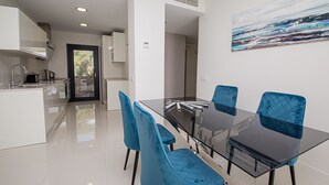 A modern kitchen with white cabinets, a black countertop, and a glass door leading to a balcony. - Paloma Beach apartment 3.2a (Manilva)