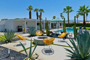 Zona junto a la piscina con sillas de descanso, cactus y una alberca.