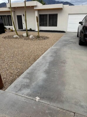A modern house with a concrete driveway, a garage, and a cactus garden.