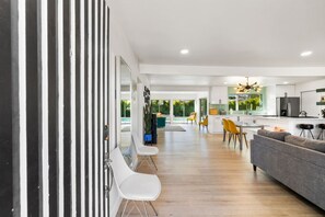 Un interior moderno con comedor, cocina y vistas al exterior.
