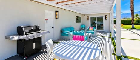 Un patio exterior con una parrilla, asientos y vistas al entorno.