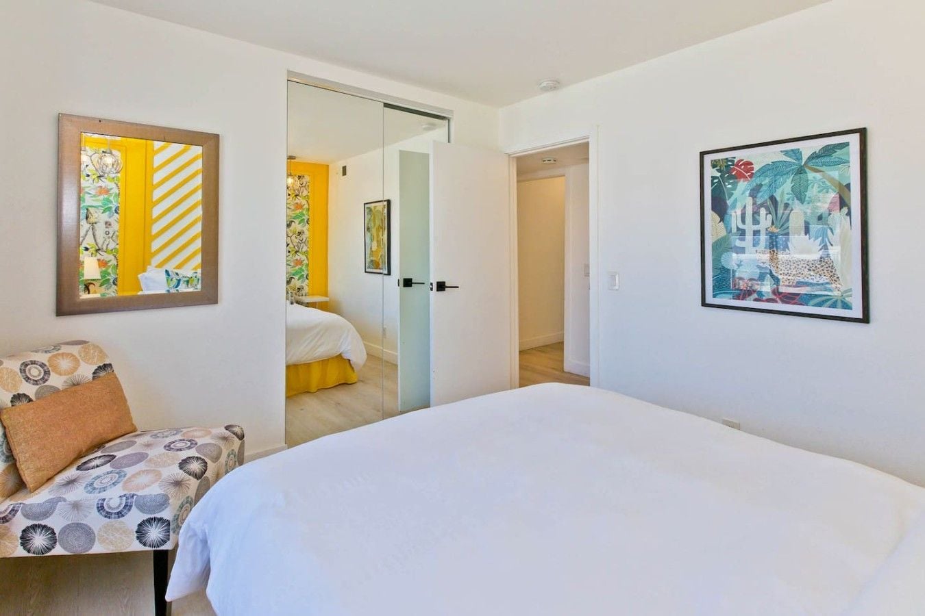 Une chambre d’hôtel avec un lit, une chaise et deux portes donnant sur d’autres pièces.