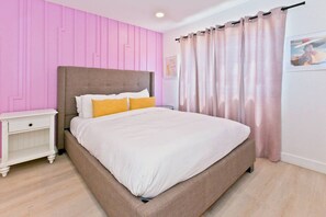 A bedroom with a bed, nightstand, and curtains.