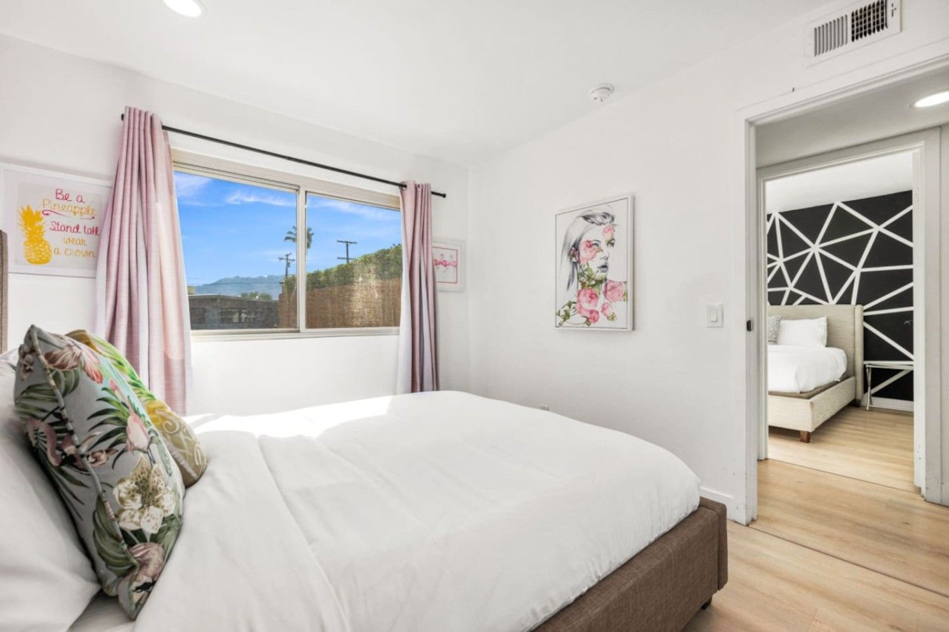Quarto com uma cama grande, janela com cortinas, quadro e vista para o exterior.