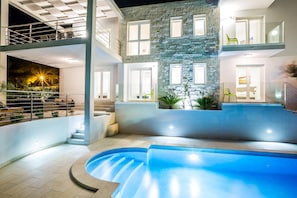 Un hotel moderno con piscina, varios balcones y fachada de piedra.