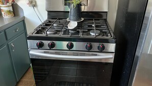 Een keuken met een roestvrijstalen fornuis, een zwarte oven en een groene kast.