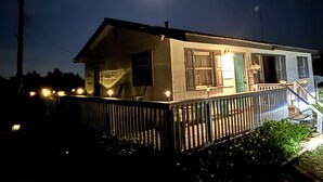Een klein, gelijkvloers huis met een veranda en een trap naar de ingang.