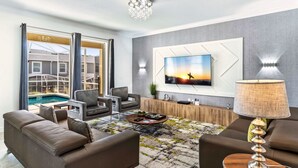 A modern living room with a pool view, a flat-screen TV, and a stylish lamp.