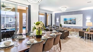 A modern dining area with a wooden table set for six, surrounded by comfortable seating.