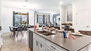 A modern kitchen with a large island, built-in appliances, and a dining area with a table and chairs.