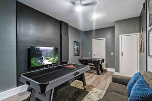 A room with a foosball table, a television, and a door.