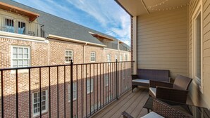 A balcony with wicker furniture and a view of brick buildings.