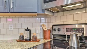 A modern kitchen with a stainless steel stove, a microwave, and a digital clock displaying 12:12.