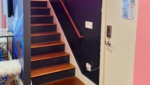 A staircase with a neon sign, a door with a QR code, and a wall-mounted light fixture.