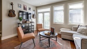 A living room with a TV, guitars, a coffee table, and a sofa.