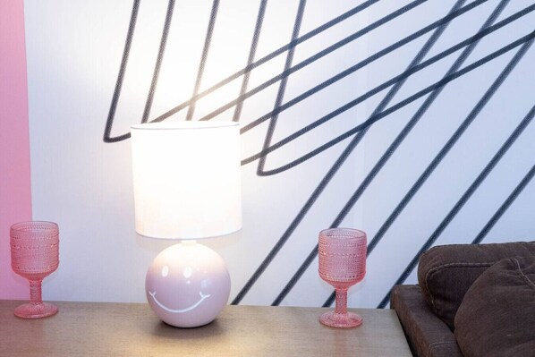 Una habitación con una lámpara moderna sobre una mesa de madera, un papel tapiz con diseño y un sofá marrón.