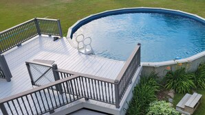 Une piscine dotée d’une terrasse en bois et d’une rambarde en métal.