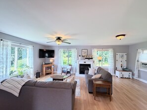 A spacious living room with a fireplace, a television, and a ceiling fan.