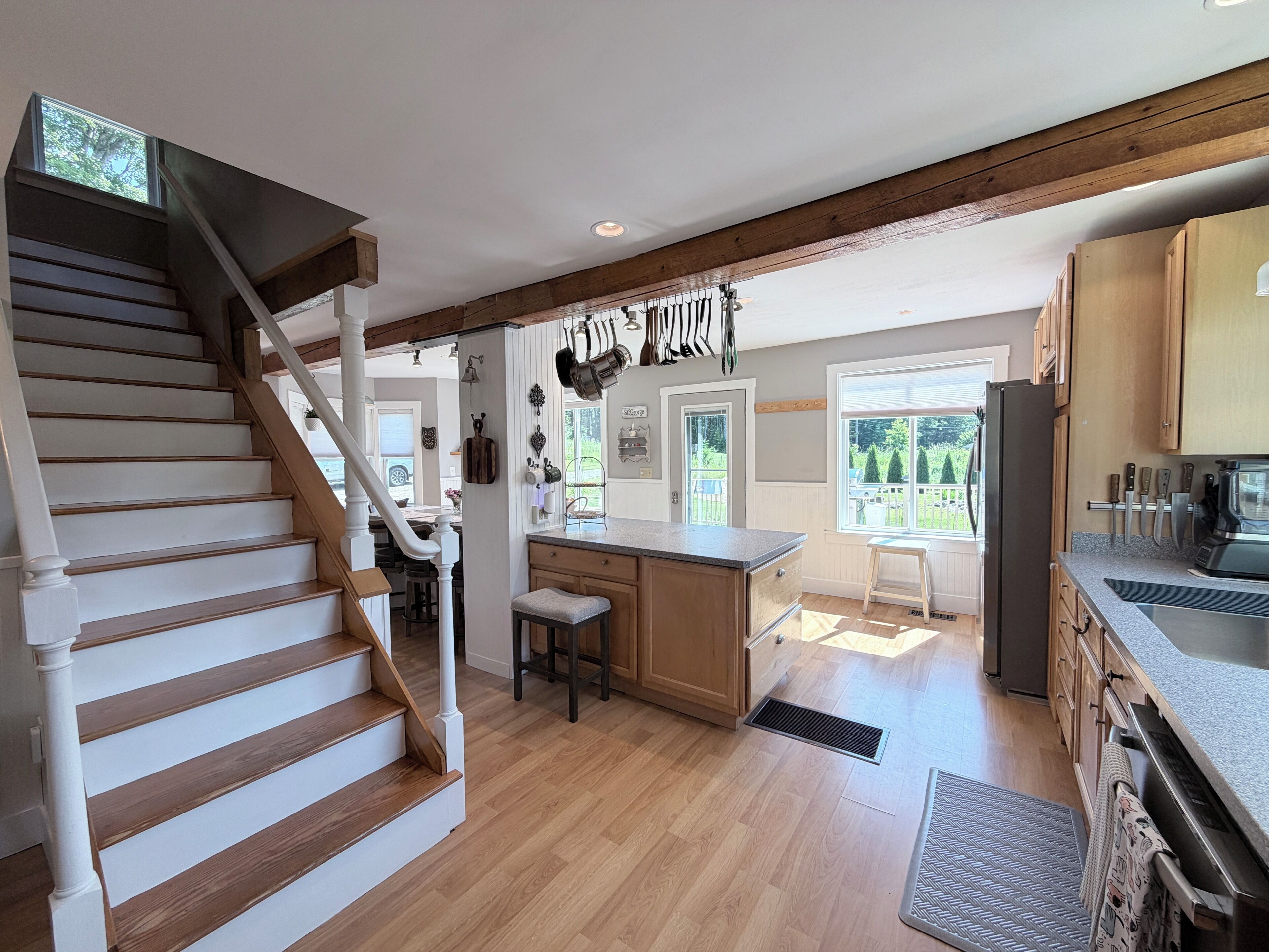 A kitchen with wooden flooring, a central island, and a refrigerator.