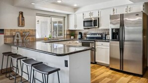 A modern kitchen with white cabinets, stainless steel appliances, and a central island with bar stools.
