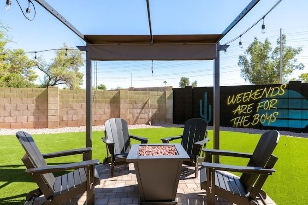 An outdoor patio with Adirondack chairs, a fire pit, and a pergola.