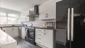 Eine moderne Küche mit weißen Schränken, einem schwarzen Kühlschrank und einem eingebauten Backofen.