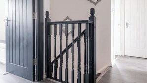Eine Treppe mit schwarzer Geländer, einer weißen Tür und einem an der Wand befestigten Spiegel.