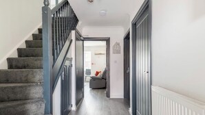 Ein Flur mit Treppe, einem grauen Sofa und einem weißen Heizkörper.