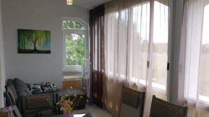 A dining area with a glass table, chairs, and a painting on the wall. - Apartments Topić - One Bedroom Apartment with Terrace (First Floor) (Privlaka)