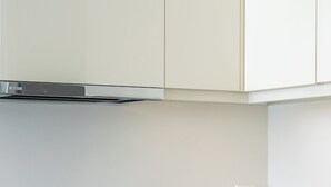 A modern kitchen with a built-in oven, white cabinetry, and a countertop. - zenvillas.gr (Lefkada)