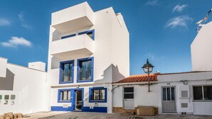 A white building with blue accents, a cobblestone street, and a clear blue sky. - Seaview Townhouse by the riverside in the centre of Alvor (with terrace) (Alvor)