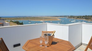 A wooden table with a bottle of champagne and two glasses on a balcony overlooking a marina with boats. - Seaview Townhouse by the riverside in the centre of Alvor (with terrace) (Alvor)