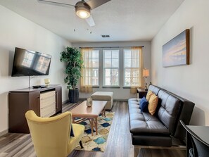 Relax in this stylish living room with a flat-screen TV, comfortable sofa, and cozy armchair.