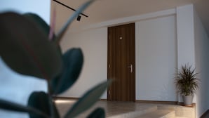 A modern interior with a wooden door, a potted plant, and a staircase leading to an upper level. - Basa Boutique Hotel (Tbilisi)