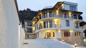 A multi-story building with balconies, a stone wall, and a driveway leading to the entrance. - Basa Boutique Hotel (Tbilisi)