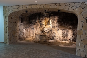 A stone fireplace with a rustic design, a patterned floor, and a ceiling light fixture. - Basa Boutique Hotel (Tbilisi)