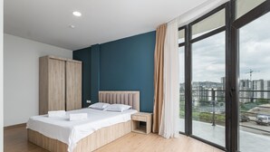 A modern bedroom with a bed, wooden wardrobe, and a view of the city through large windows. - Basa Boutique Hotel (Tbilisi)