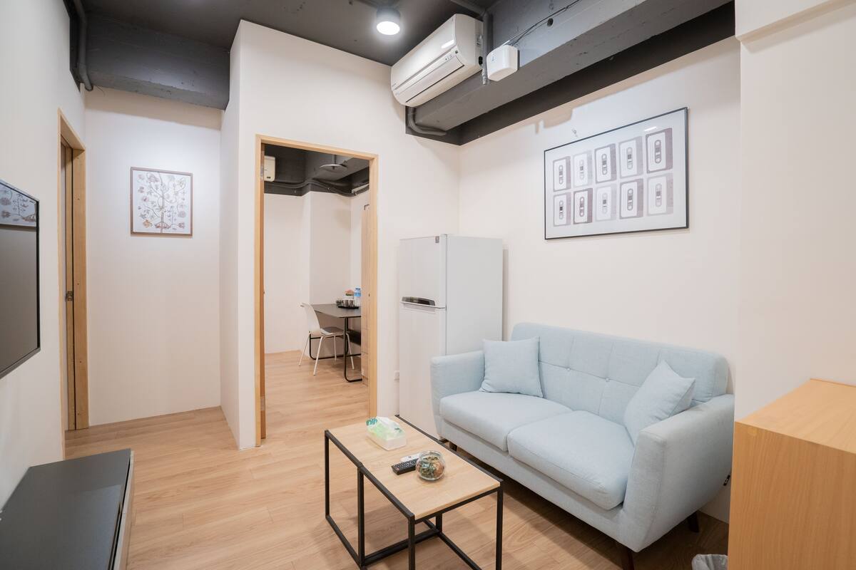 A modern living room with a light blue sofa, a coffee table, and a flat-screen TV.