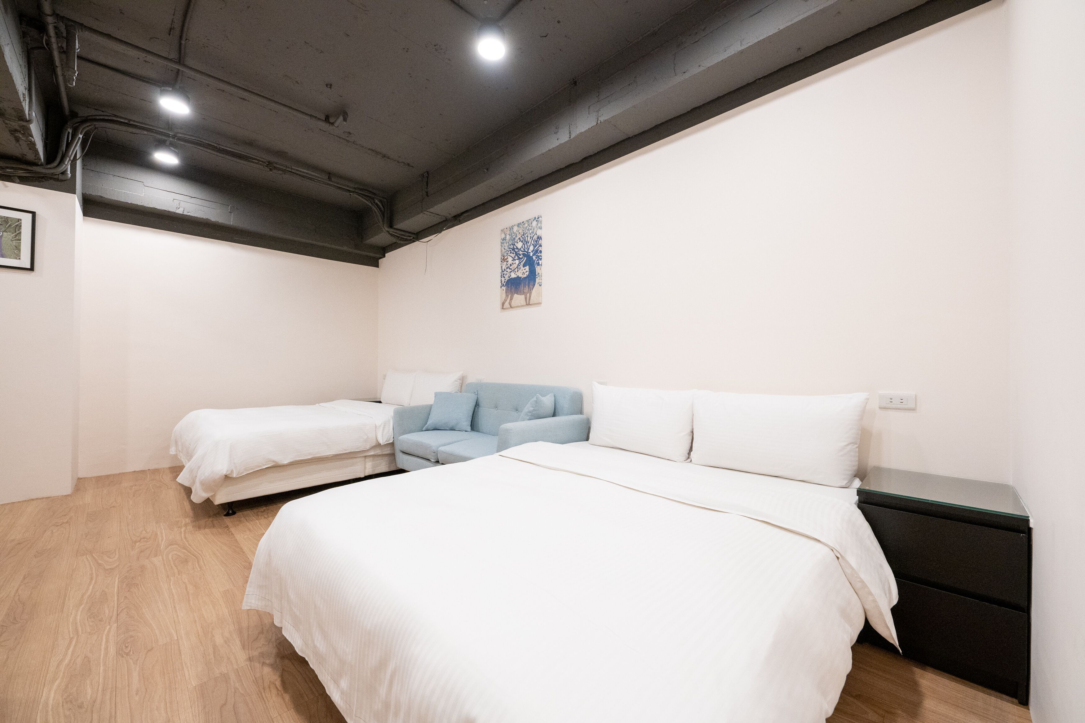 A bedroom with a large bed, a smaller bed, a sofa, and a nightstand.
